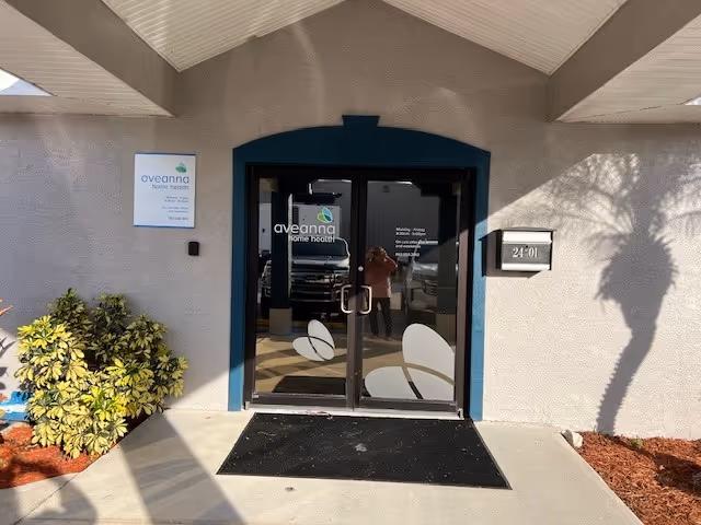 Exterior view of Aveanna Home Health entrance with glass doors and surrounding landscaping.
