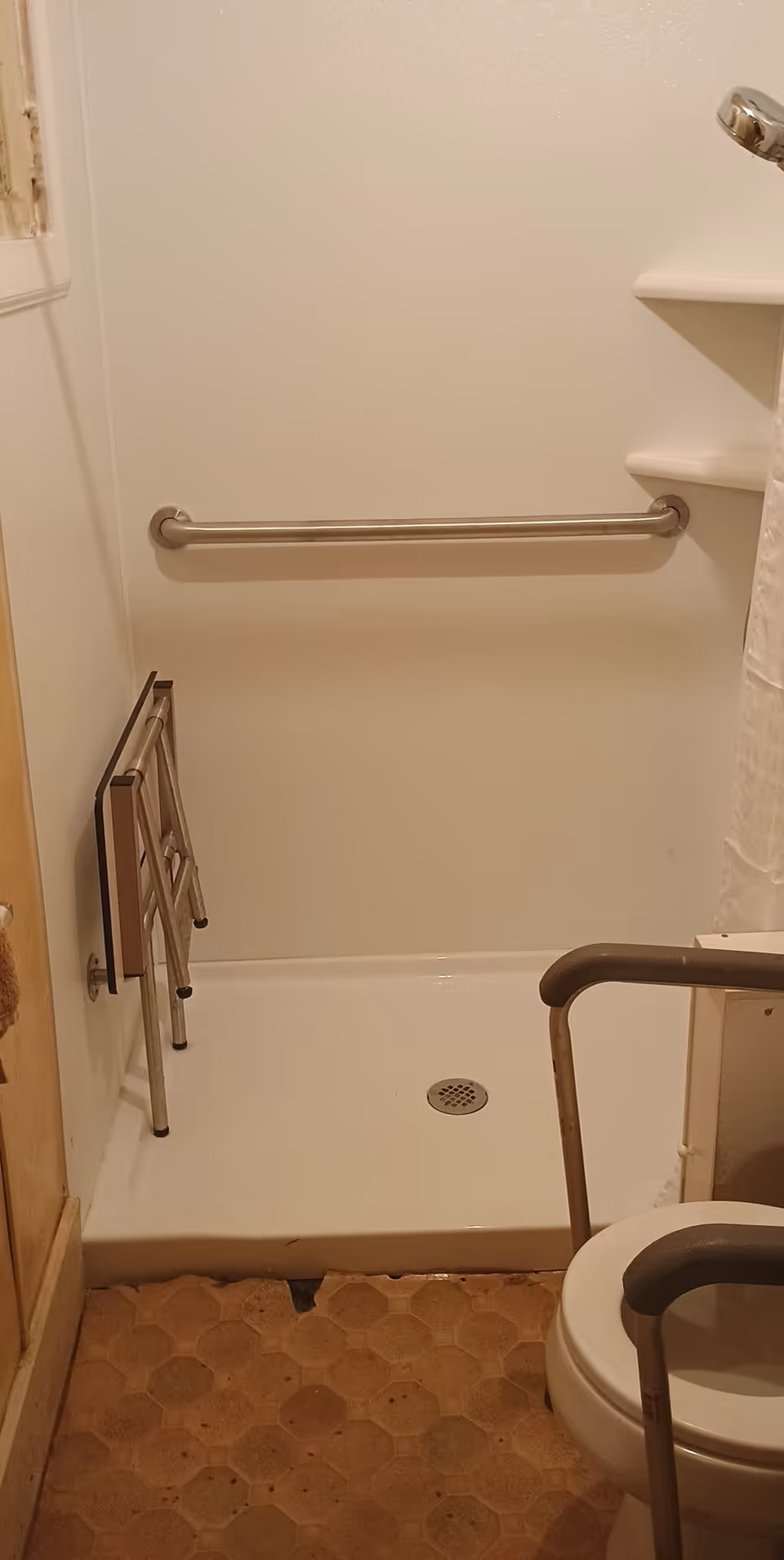 Accessible bathroom with grab bars, a shower stall, and mobility aids.