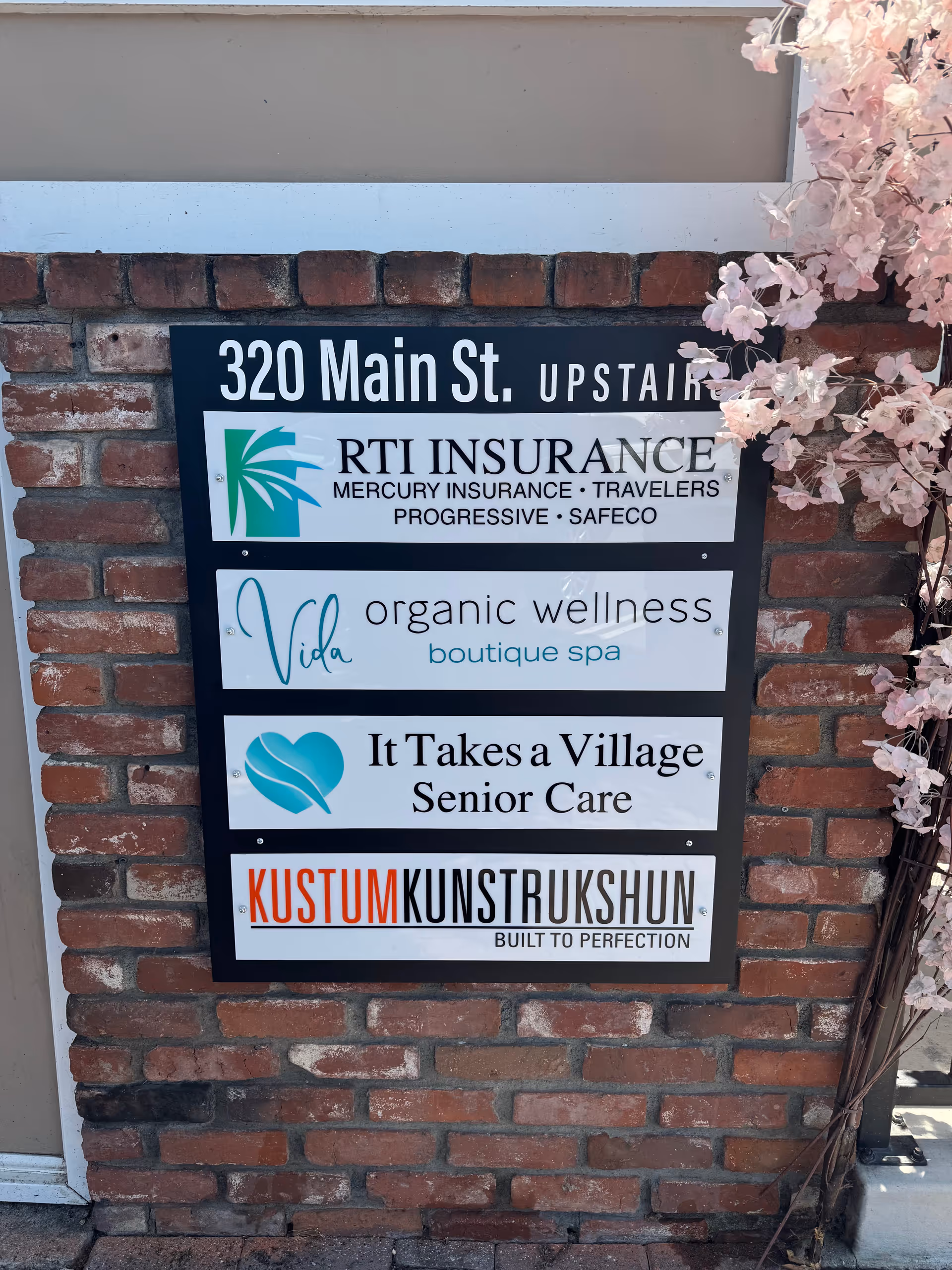 Brick exterior wall featuring a multi-panel signboard for It Takes a Village Senior Care.