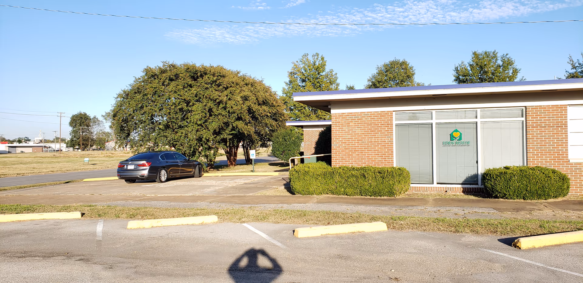 Exterior view of Eden House facility: brick building with parking lot and trimmed hedges.