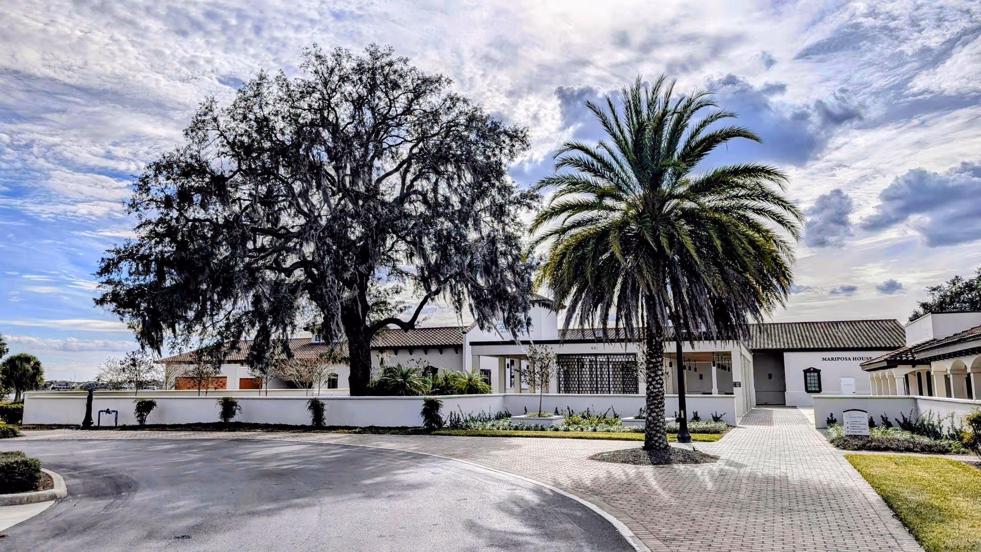 Exterior view of Cornerstone Hospice facility with palm trees, walkway, and white buildings.