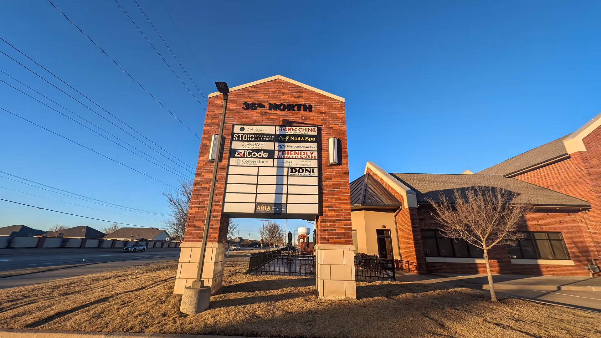 Brick building with a tall multi-tenant sign under a clear blue sky.