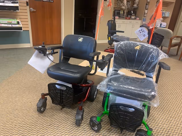 Two mobility scooters parked in a carpeted lobby area inside a senior care facility.