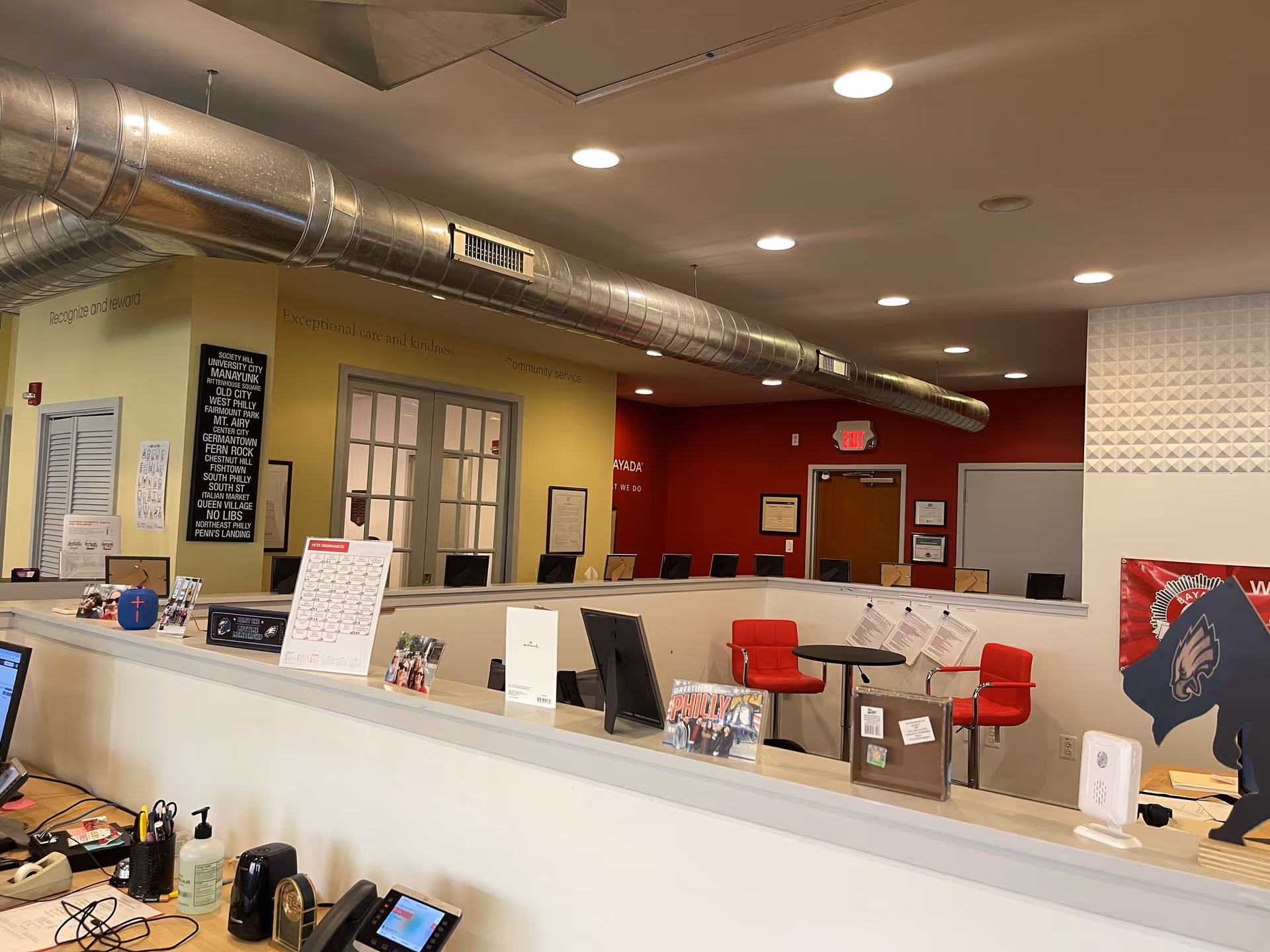 Indoor reception area with a long counter, red chairs, and signage.