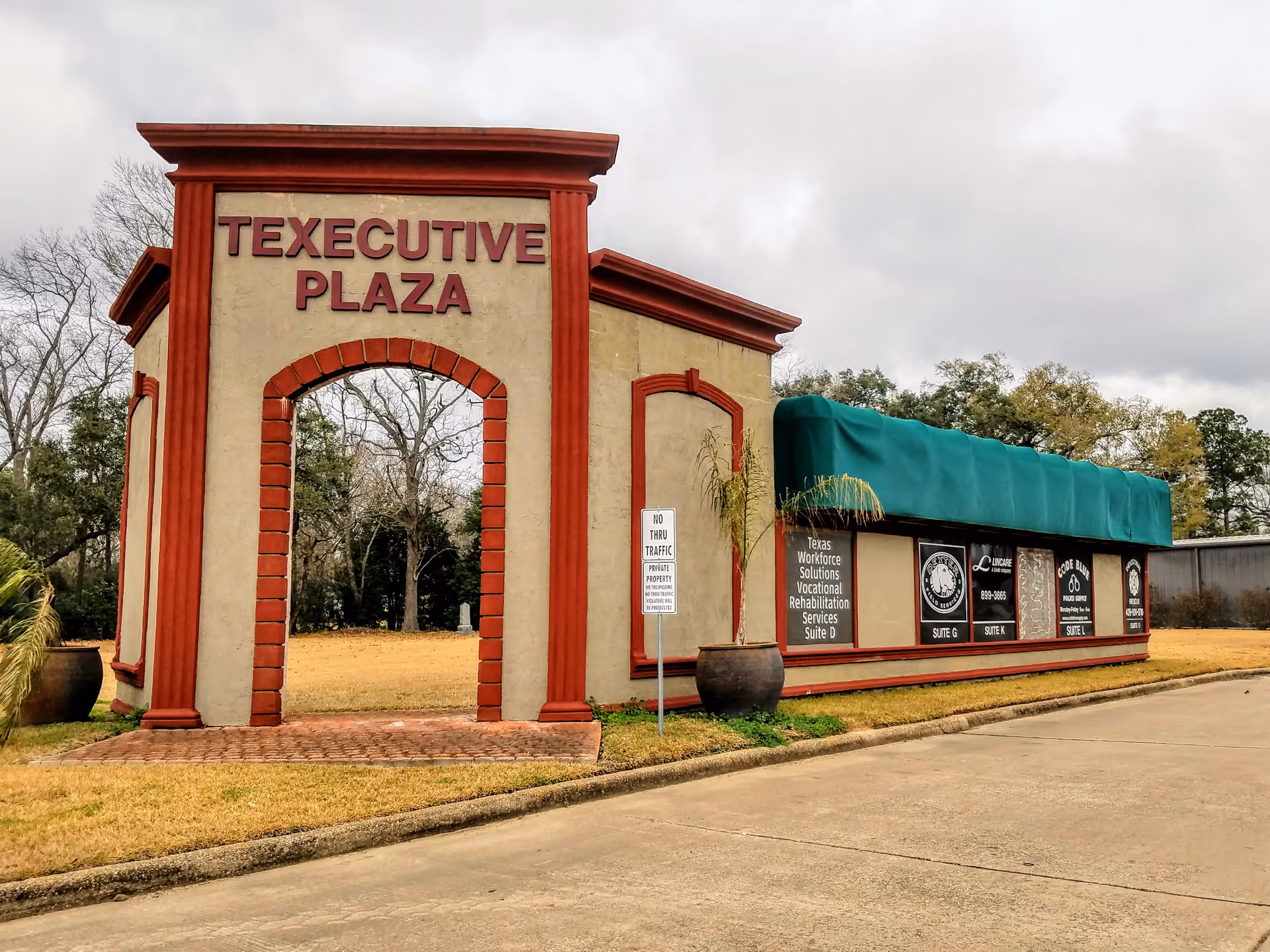 Front view of a building with a red-trimmed archway reading Texecutive Plaza.