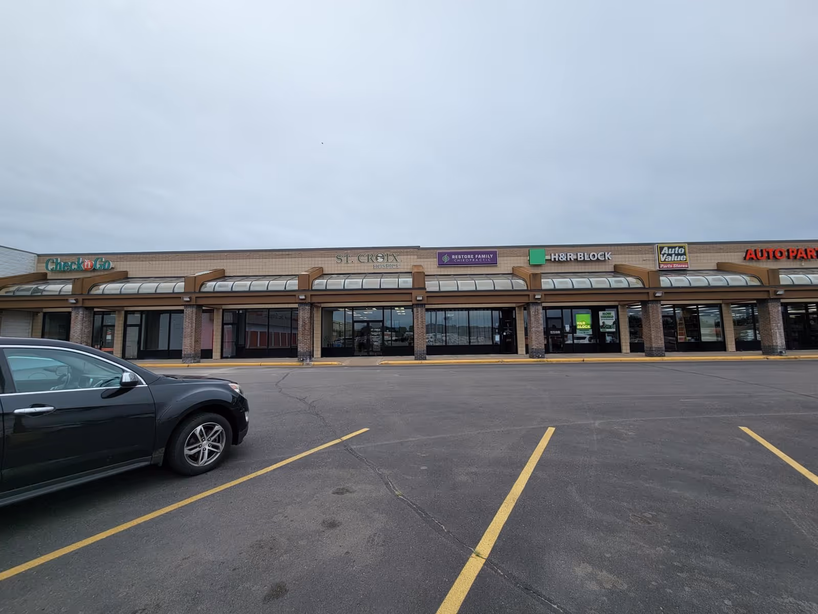 Exterior of a strip mall with St. Croix Hospice signage among other storefronts.
