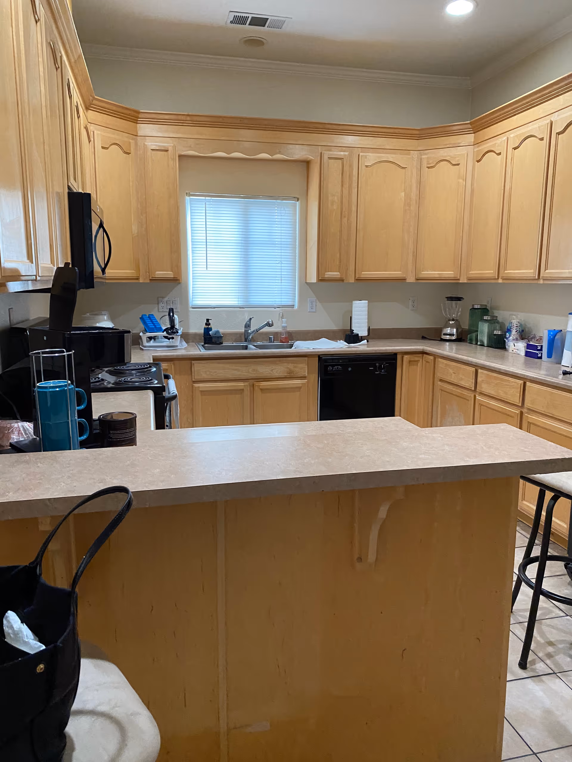 Bright kitchen with wooden cabinets, an island, sink, and appliances.