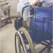 Close-up of a wheelchair with blue striped upholstery inside a facility.