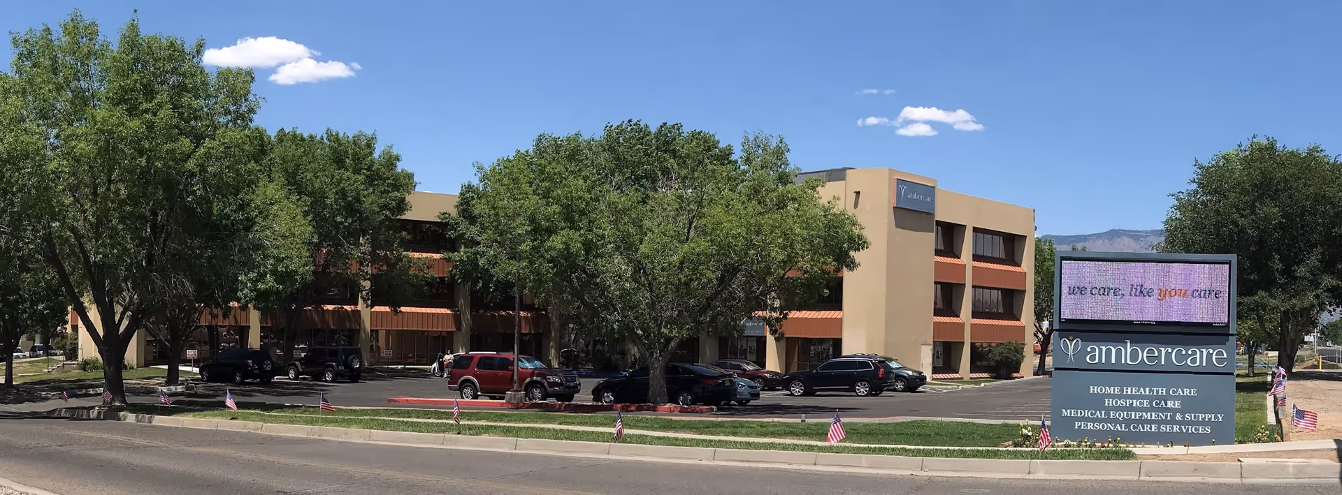 Exterior view of Ambercare senior living facility with trees, parking, and a large sign.