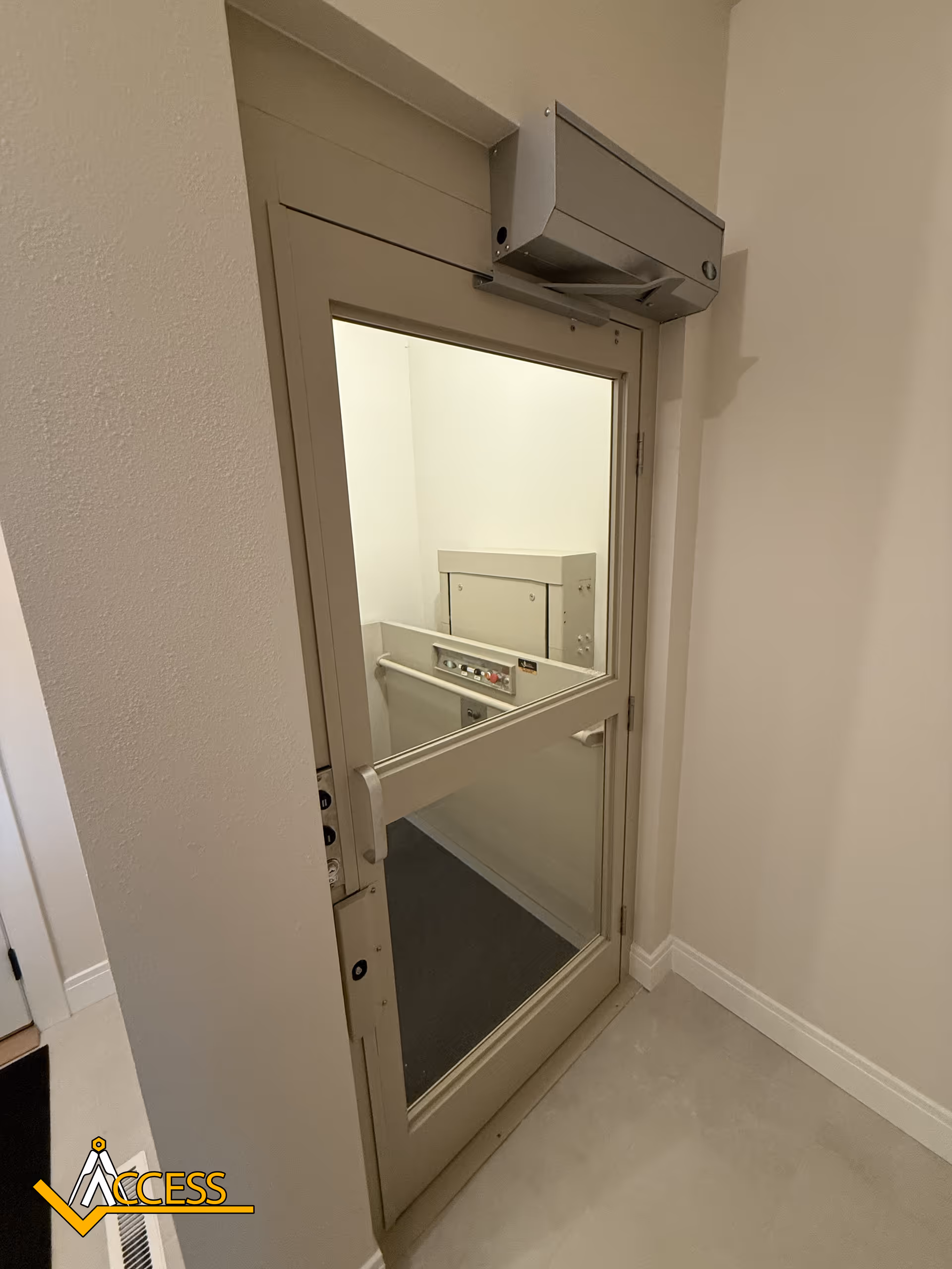 Beige interior elevator door with window and control panel visible inside.