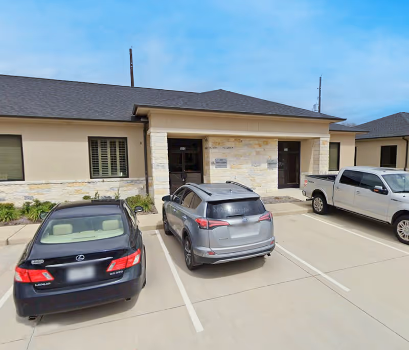 Senior living facility with stone facade, entrance doors, and parked cars in the front.