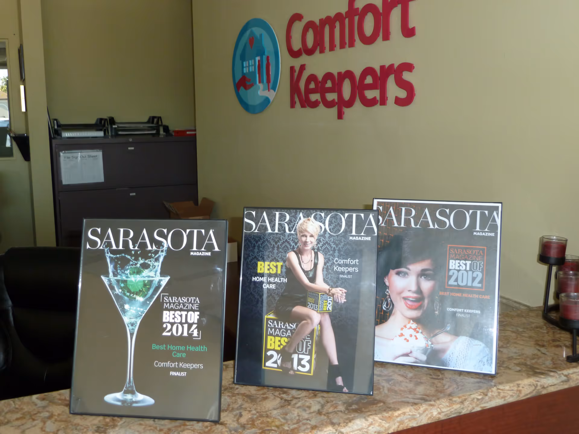 Lobby reception area with Comfort Keepers logo on wall and magazines on marble counter.