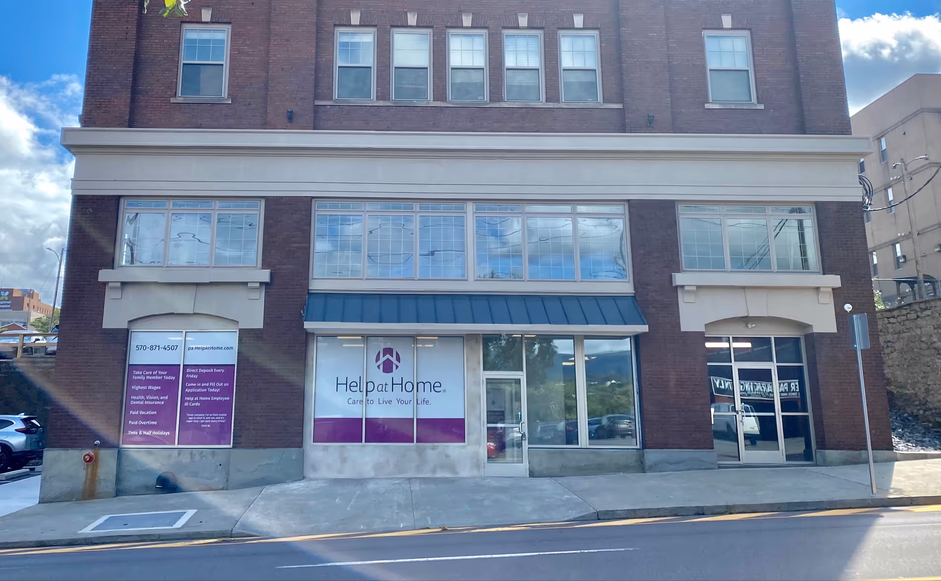 Brick storefront building with Help at Home sign and large front windows.