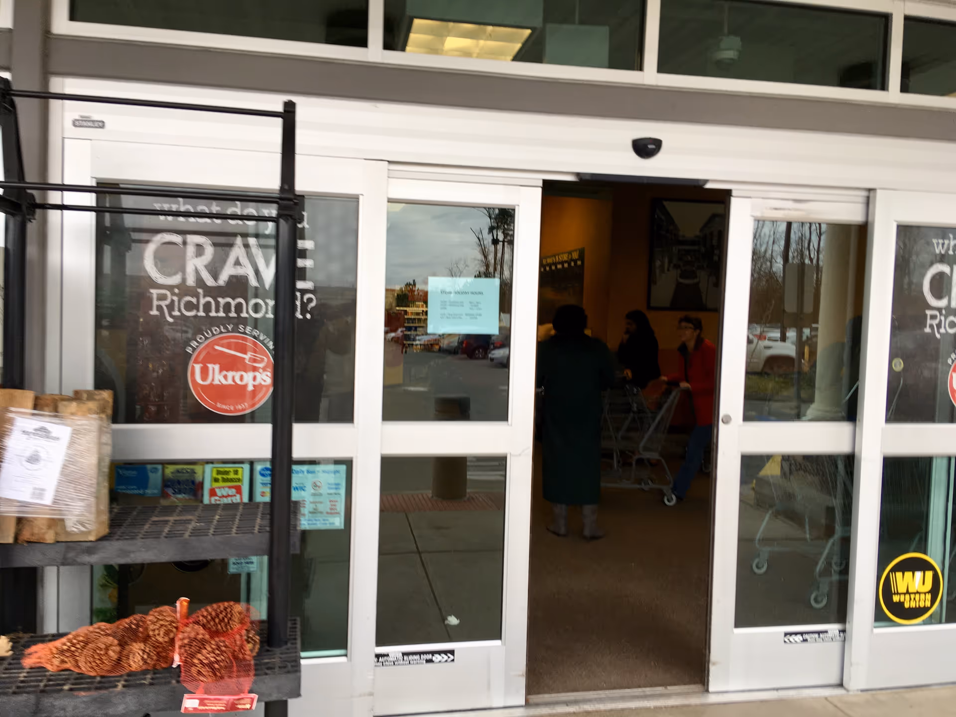 Front view of a Kroger Pharmacy entrance with glass doors and shoppers nearby.