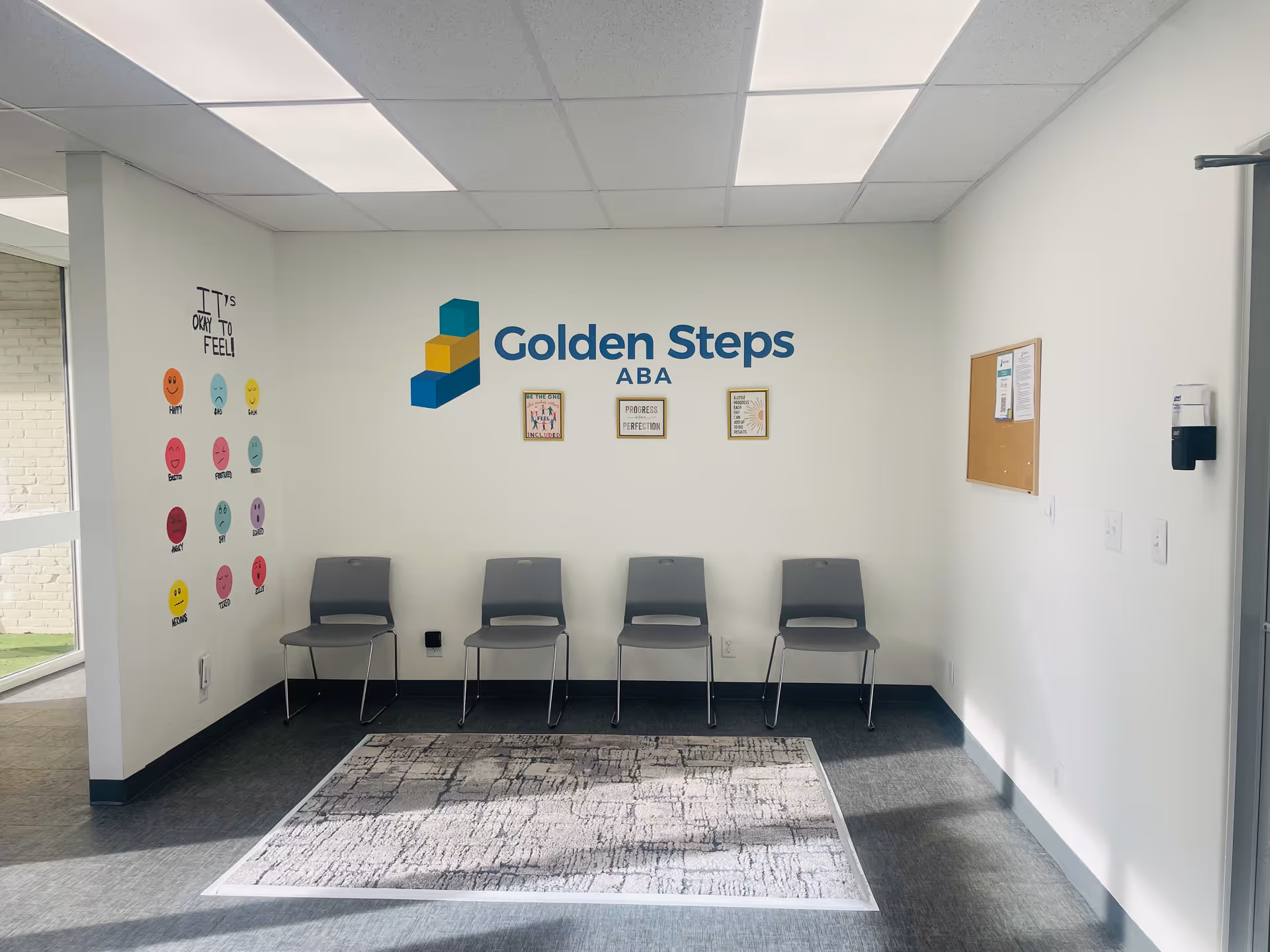 Interior waiting area with five gray chairs and Golden Steps ABA logo on wall.
