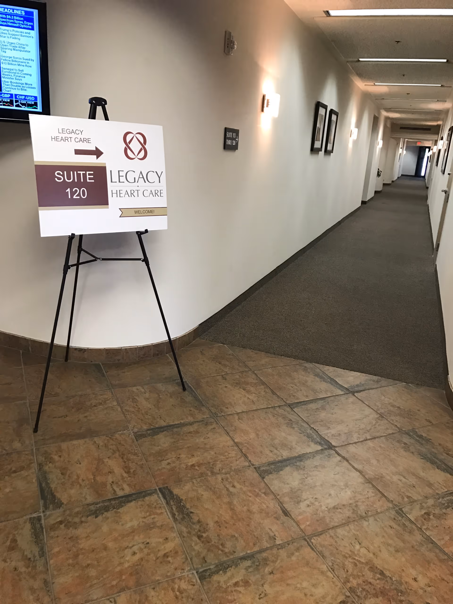 Interior hallway with a signboard for Suite 120 Legacy Heart Care near tiled floor.