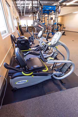 Interior rehab gym with NuStep machines and cardio equipment along walls.