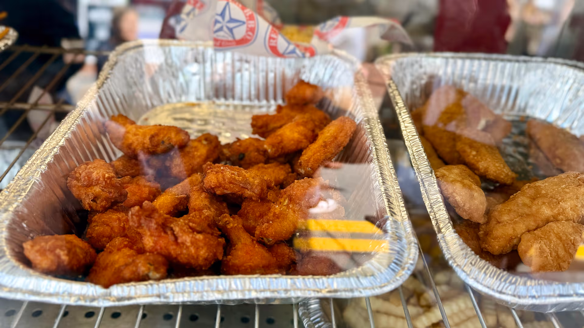 Aluminum trays of fried foods displayed on a counter.