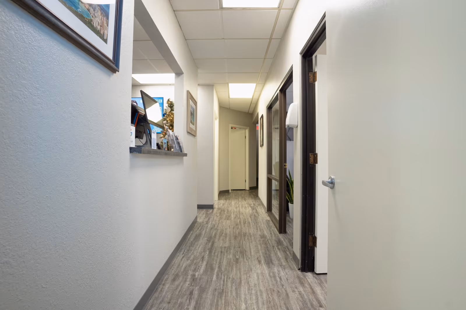 Long, well-lit hallway with a reception desk on the left and several closed doors.