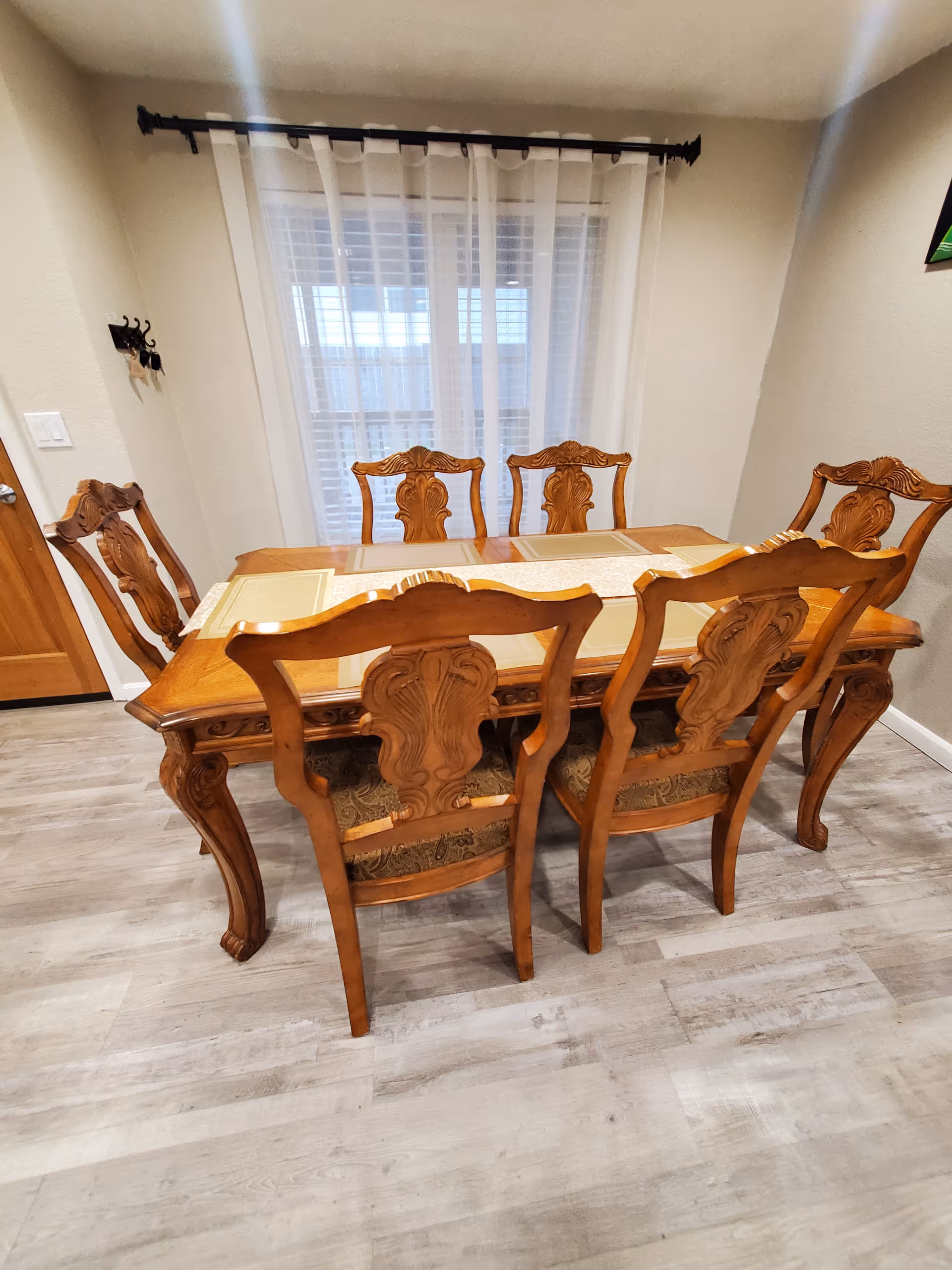Ornate wooden dining table with matching chairs in a well-lit dining room.