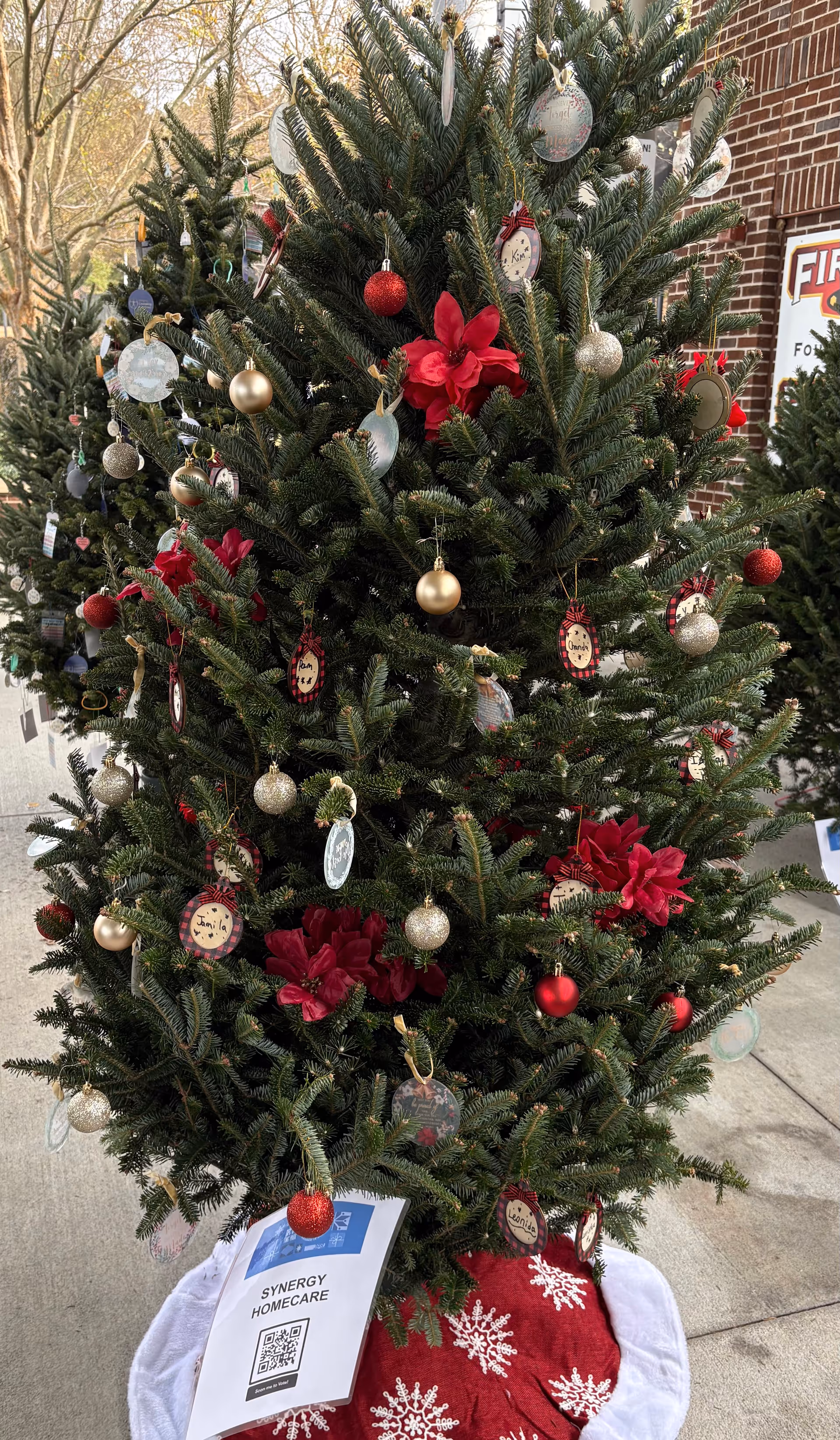 Decorated Christmas tree outside a brick SYNERGY HomeCare facility.