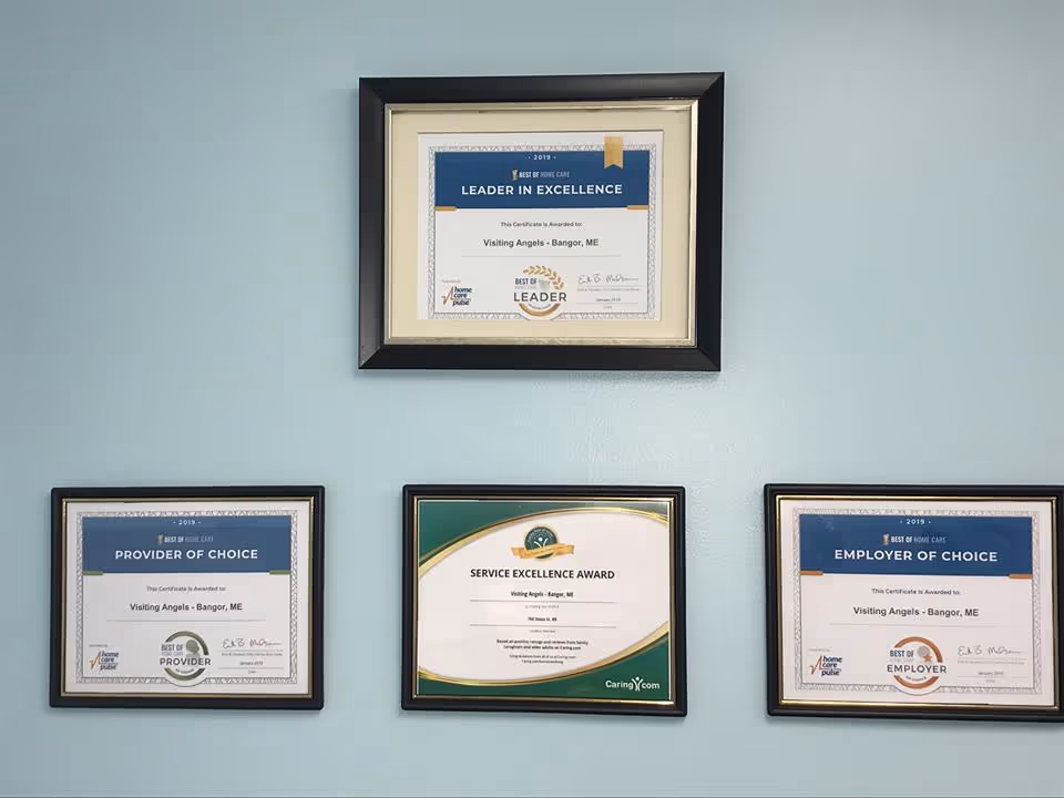 Blue wall displaying four framed certificates and awards for Visiting Angels Senior Home Care.