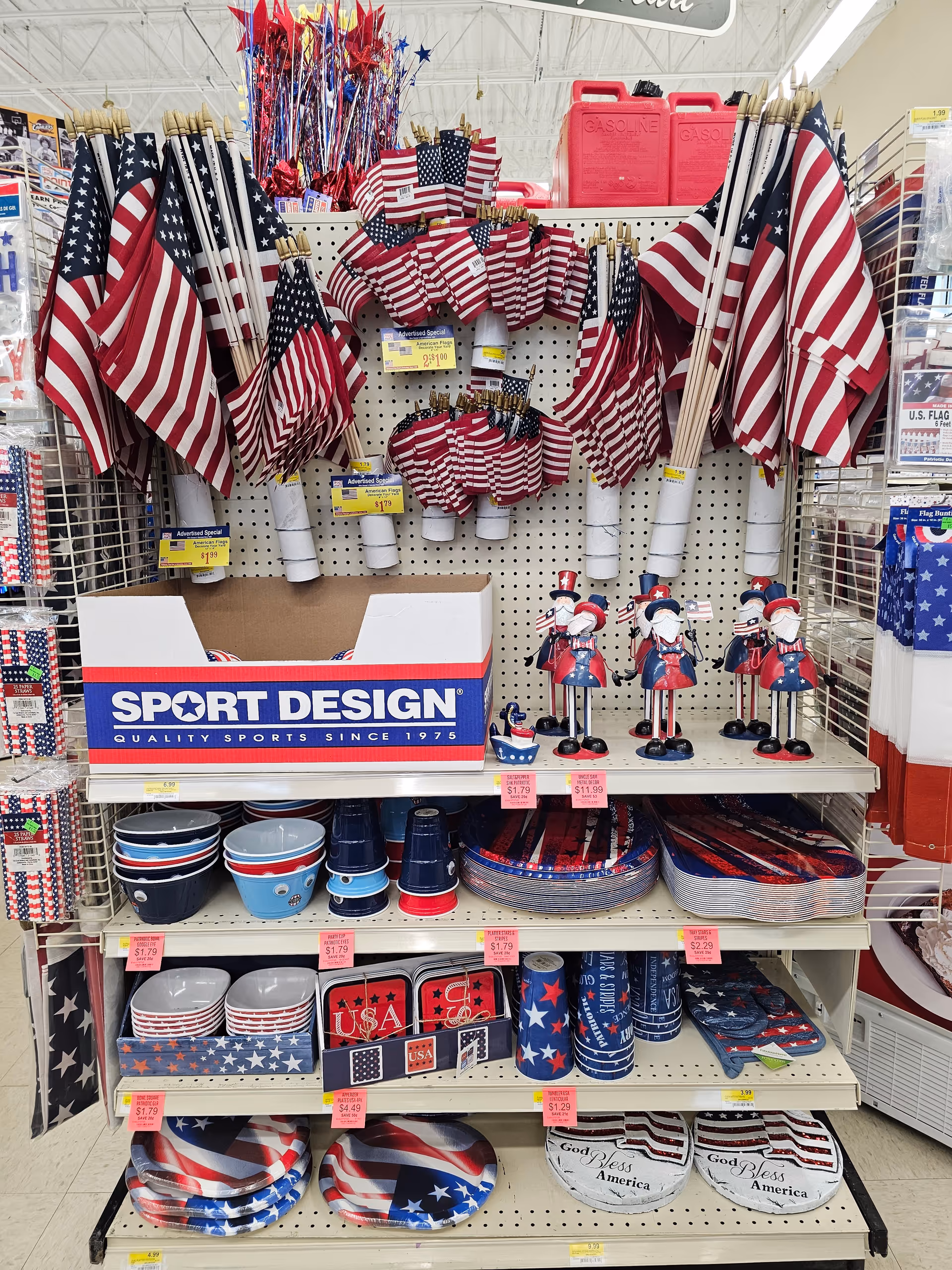 Indoor store aisle displaying patriotic flags, dishes, and decor on shelves.