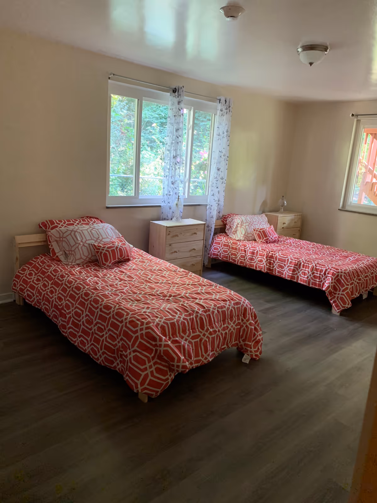 Two single beds with red geometric bedspreads in a shared bedroom with nightstands