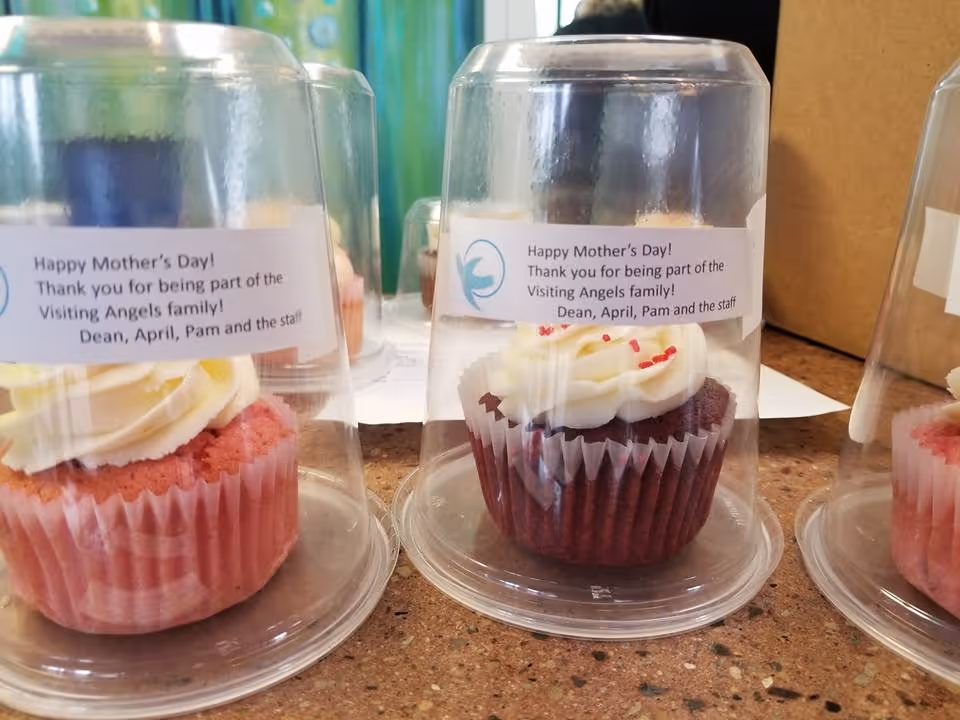 Cupcakes under clear domes with Mother's Day labels on a kitchen counter.