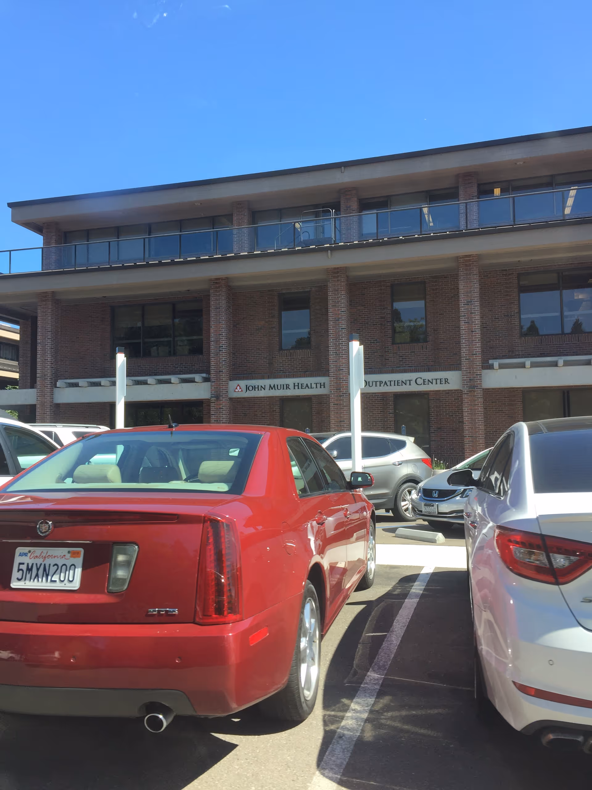 An exterior brick medical building with parked cars in a lot.