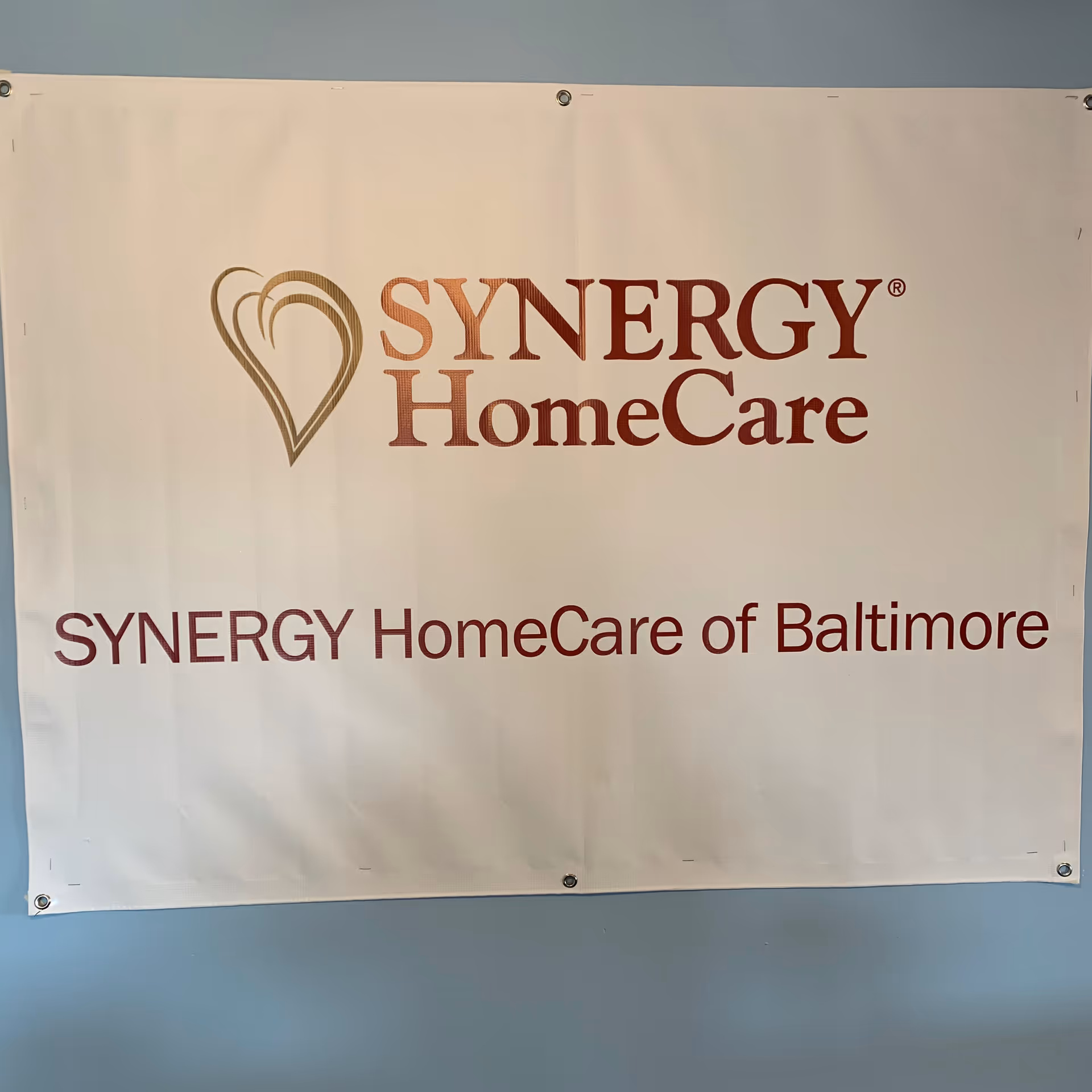 Indoor banner on a blue wall displays SYNERGY HomeCare and SYNERGY HomeCare of Baltimore.