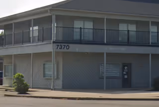 Exterior view of a two-story building with balcony and entrance, address 7370.