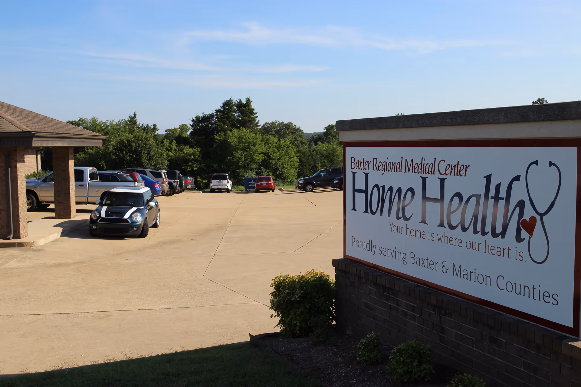 Sunlit parking lot beside a large sign reading Home Health near Baxter Regional Medical Center.