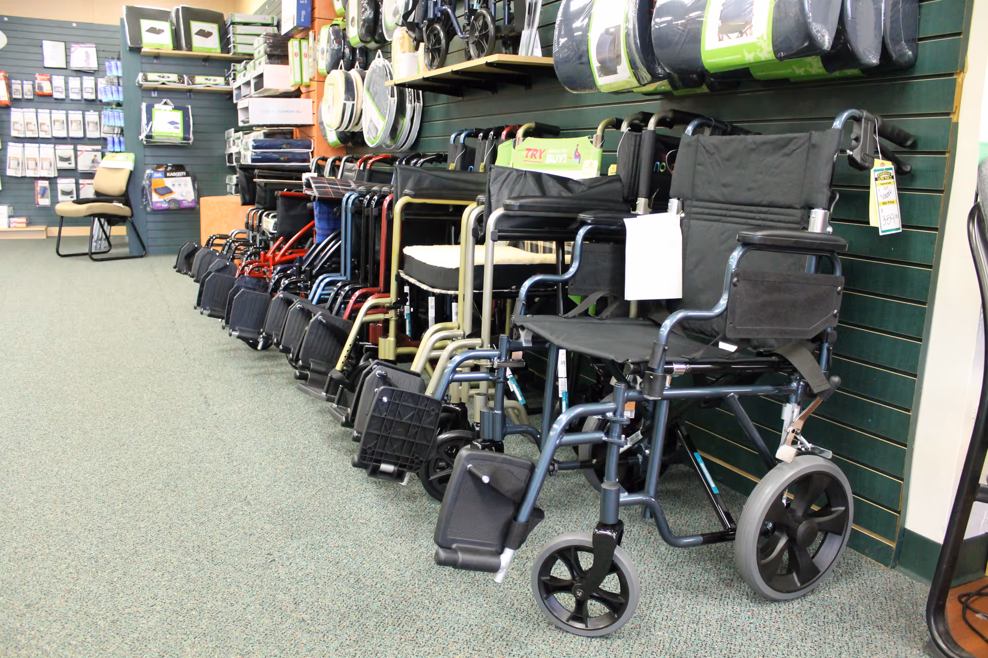 Interior showroom displaying mobility aids, including wheelchairs and walkers, against green wall slats.