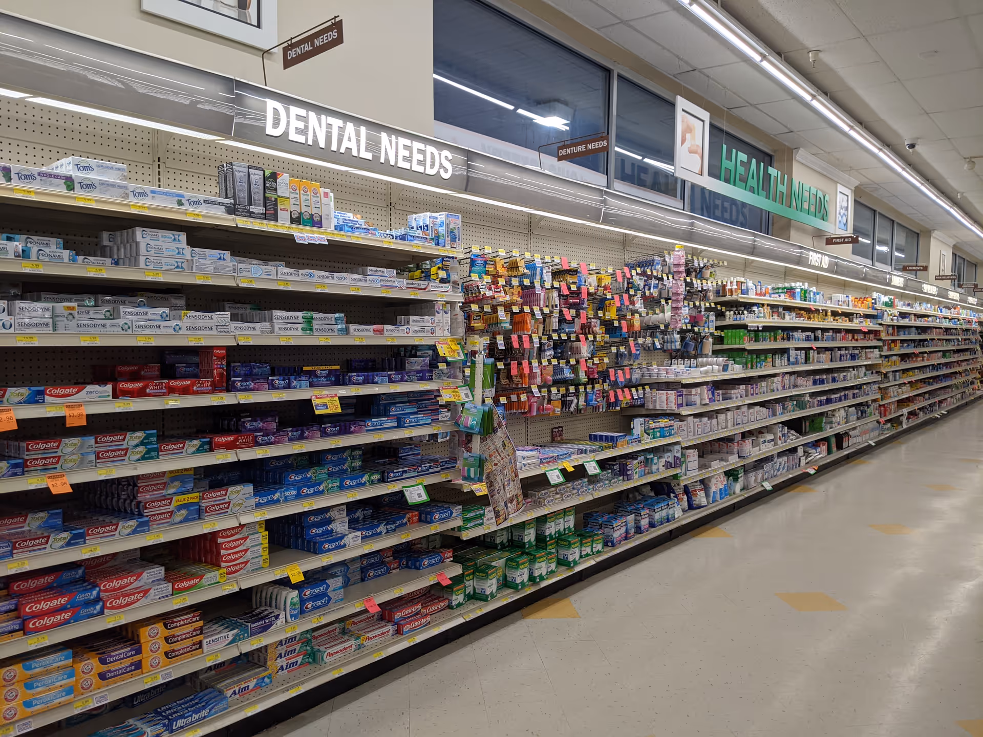 Indoor store aisle with dental and health care products on shelves.