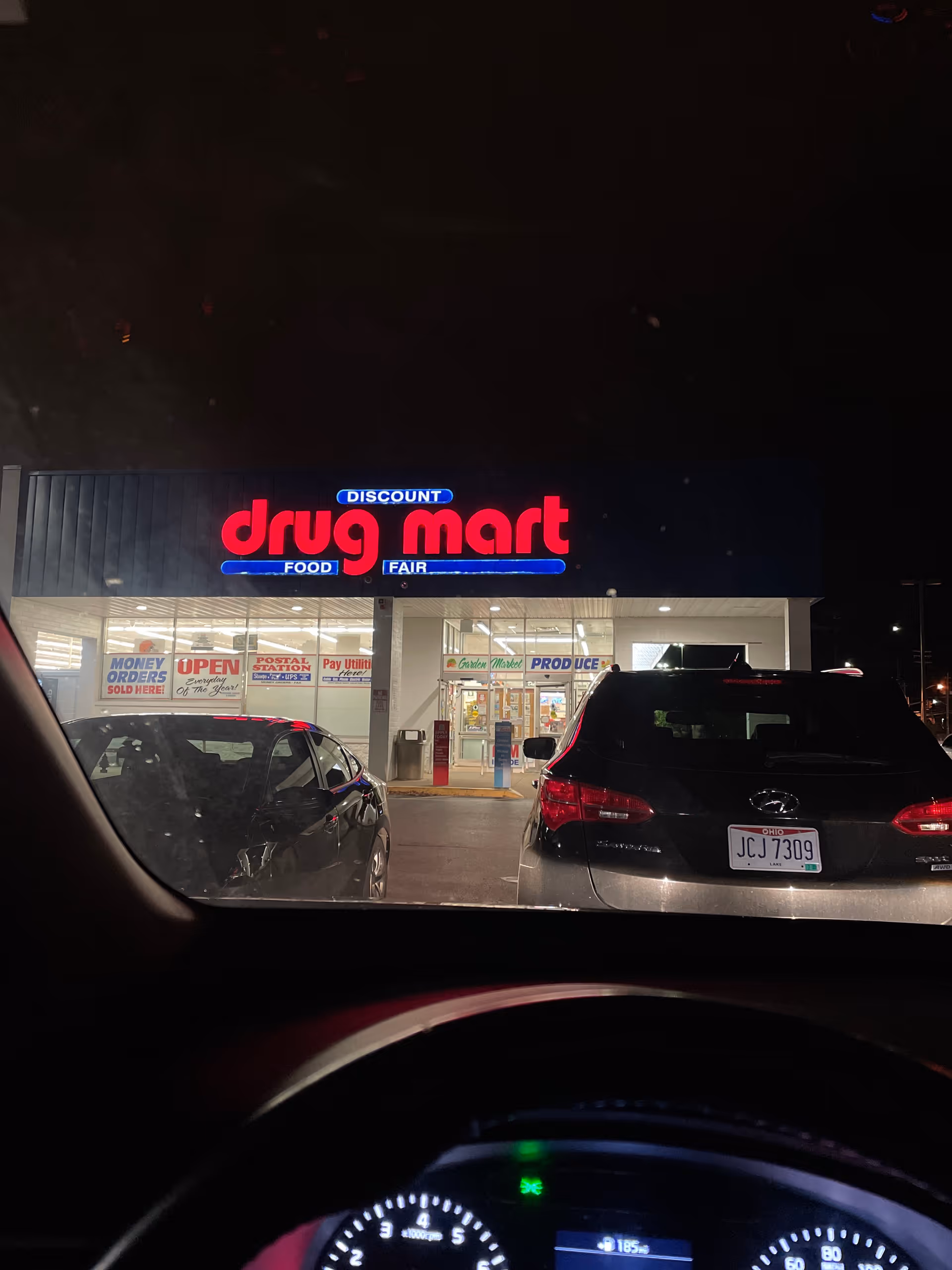 Night-time view of a Discount Drug Mart storefront seen from inside a car.
