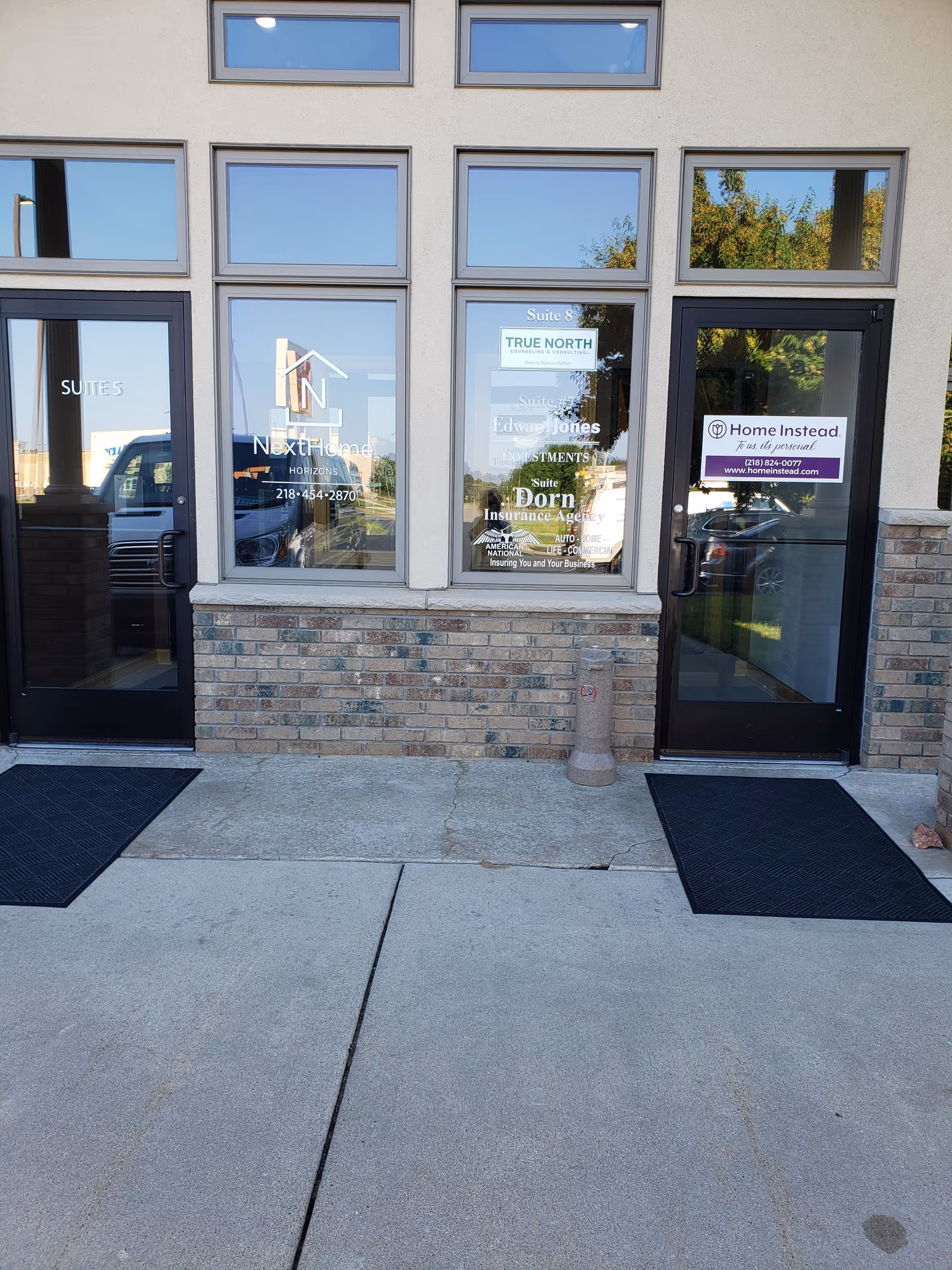 Exterior view of a facility entrance with glass doors and window signage.