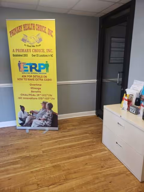 Yellow Primary Health Choice banner stands in a hallway beside a white desk.