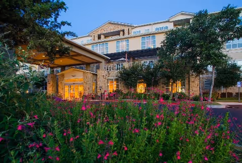 Exterior view of Longhorn Village senior living facility with a landscaped front and entry canopy.