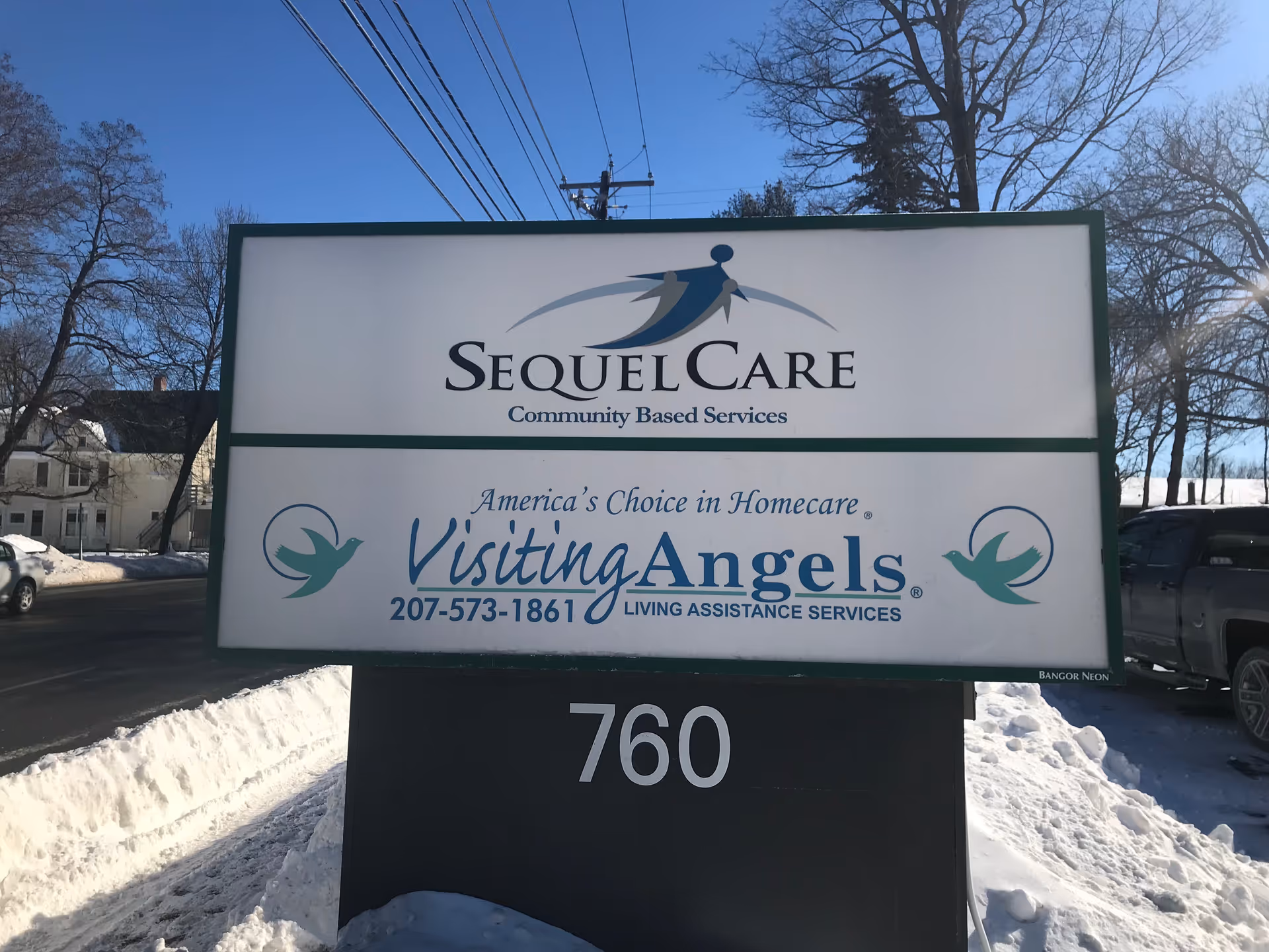 Exterior signboard displays SequelCare and Visiting Angels logos on a snowy street.