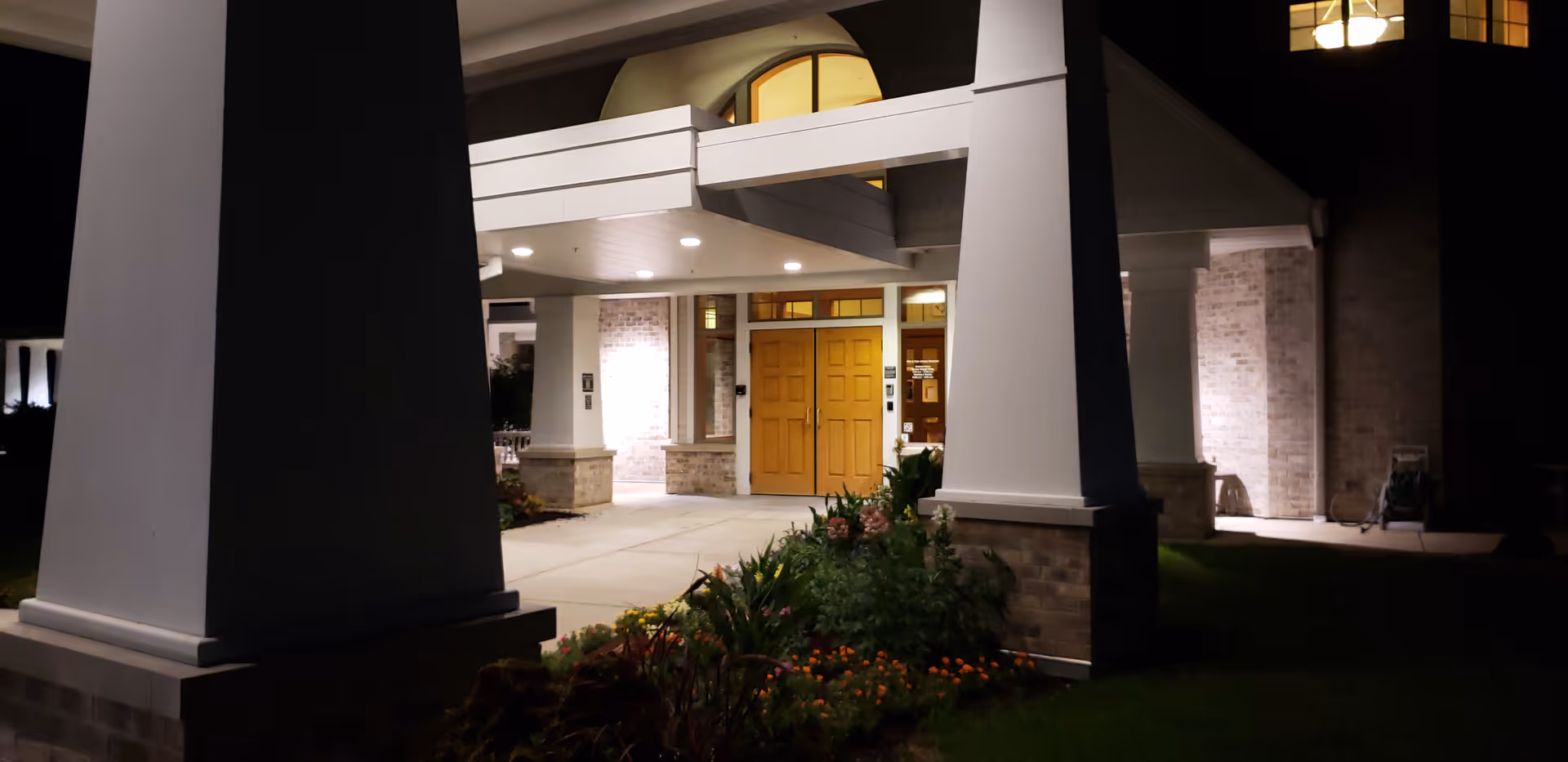 Nighttime exterior view of Agrace senior living facility entrance with illuminated doors.
