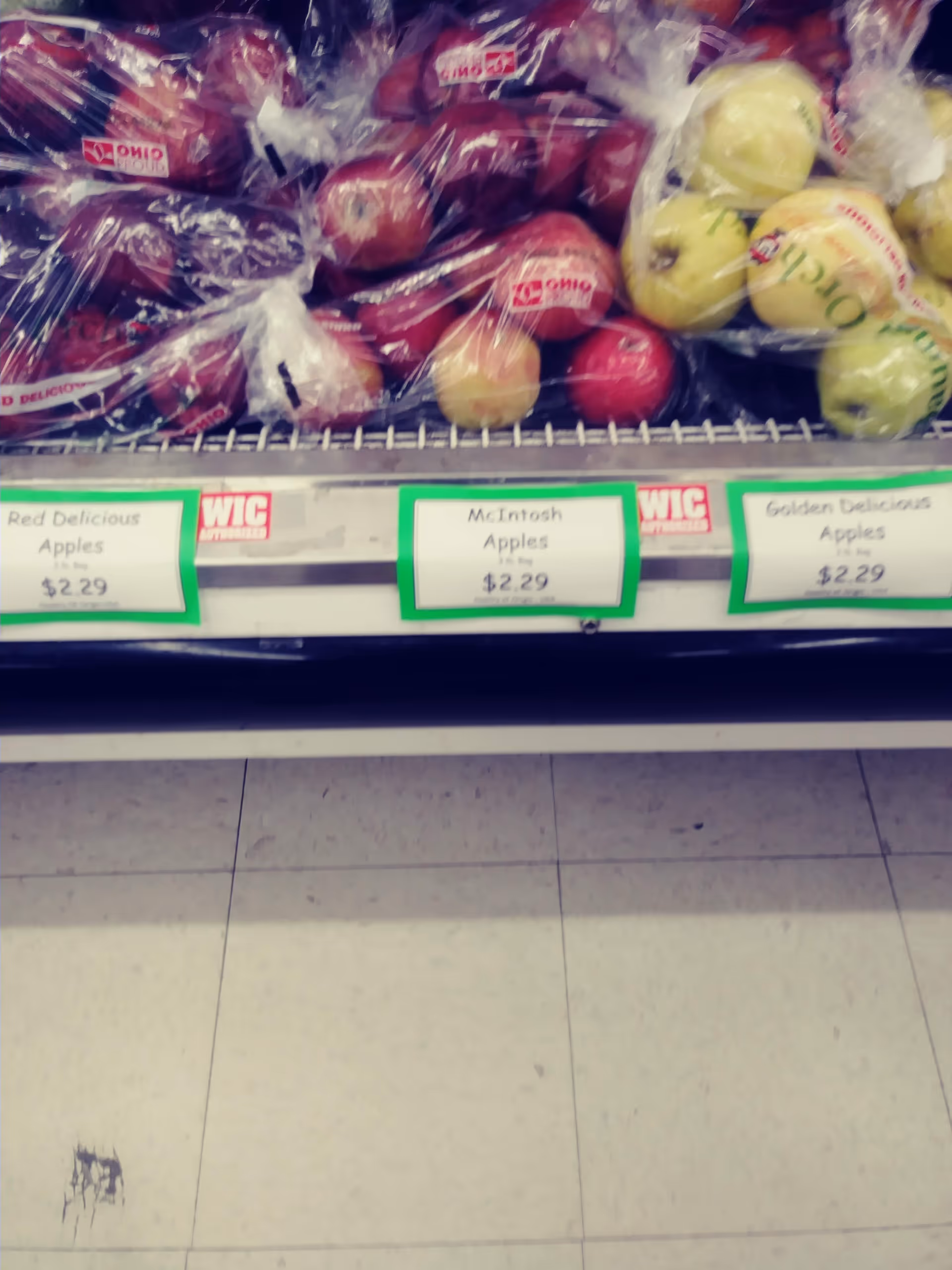 Apples displayed on a grocery-store shelf with price tags visible.