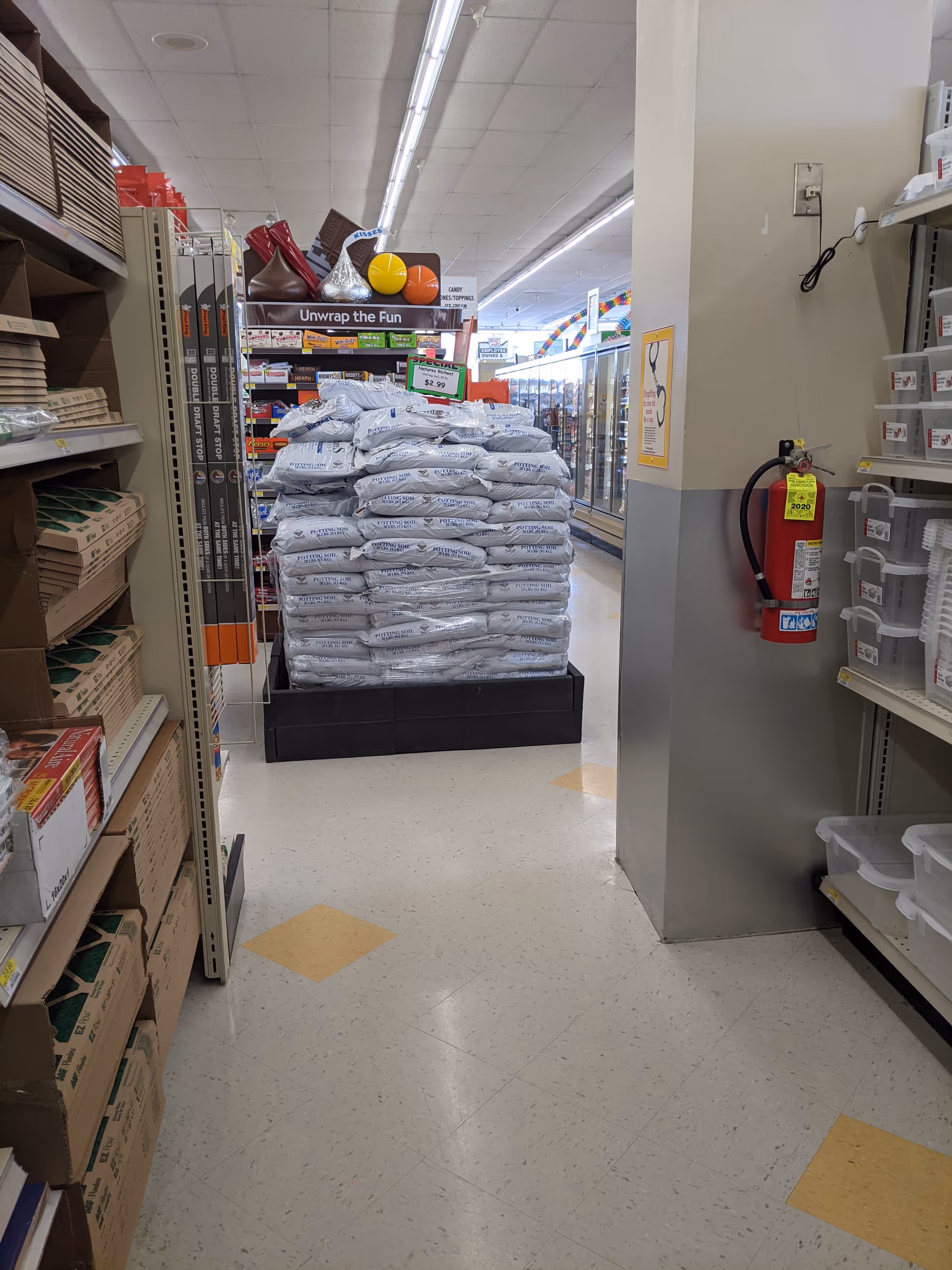 Discount Drug Mart aisle with stacked bags on a pallet beside shelves.