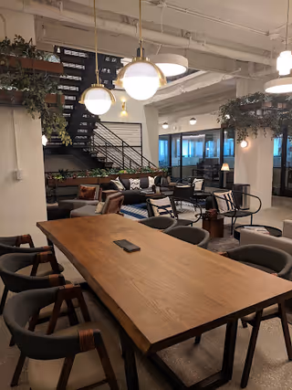 Modern communal dining area with a long wooden table and surrounding chairs.