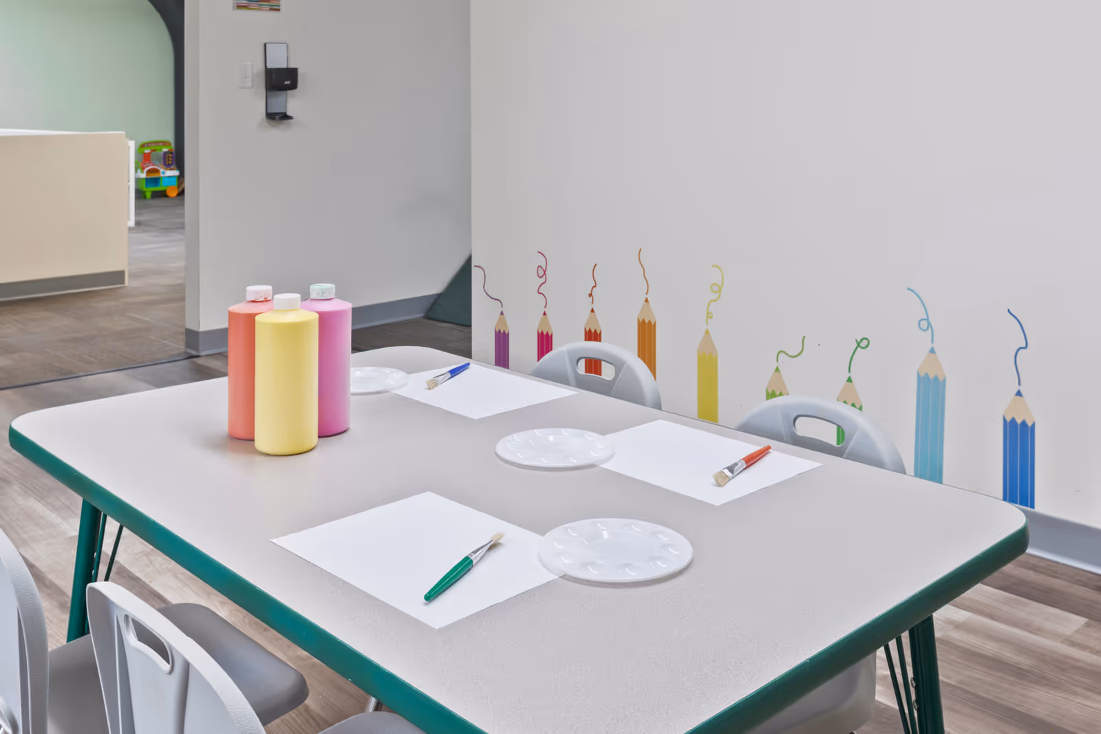 Craft table with paints, brushes, and paper in a senior living facility activity room.