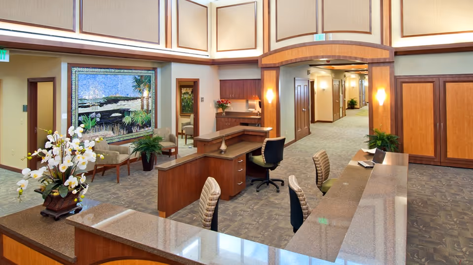 Reception desk with seating, plants, and artwork in a spacious hospice lobby