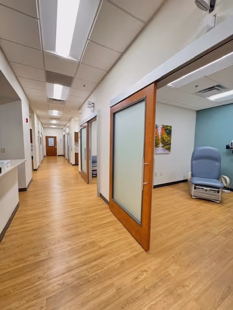 Long hallway inside a senior living facility with closed doors and a blue recliner.