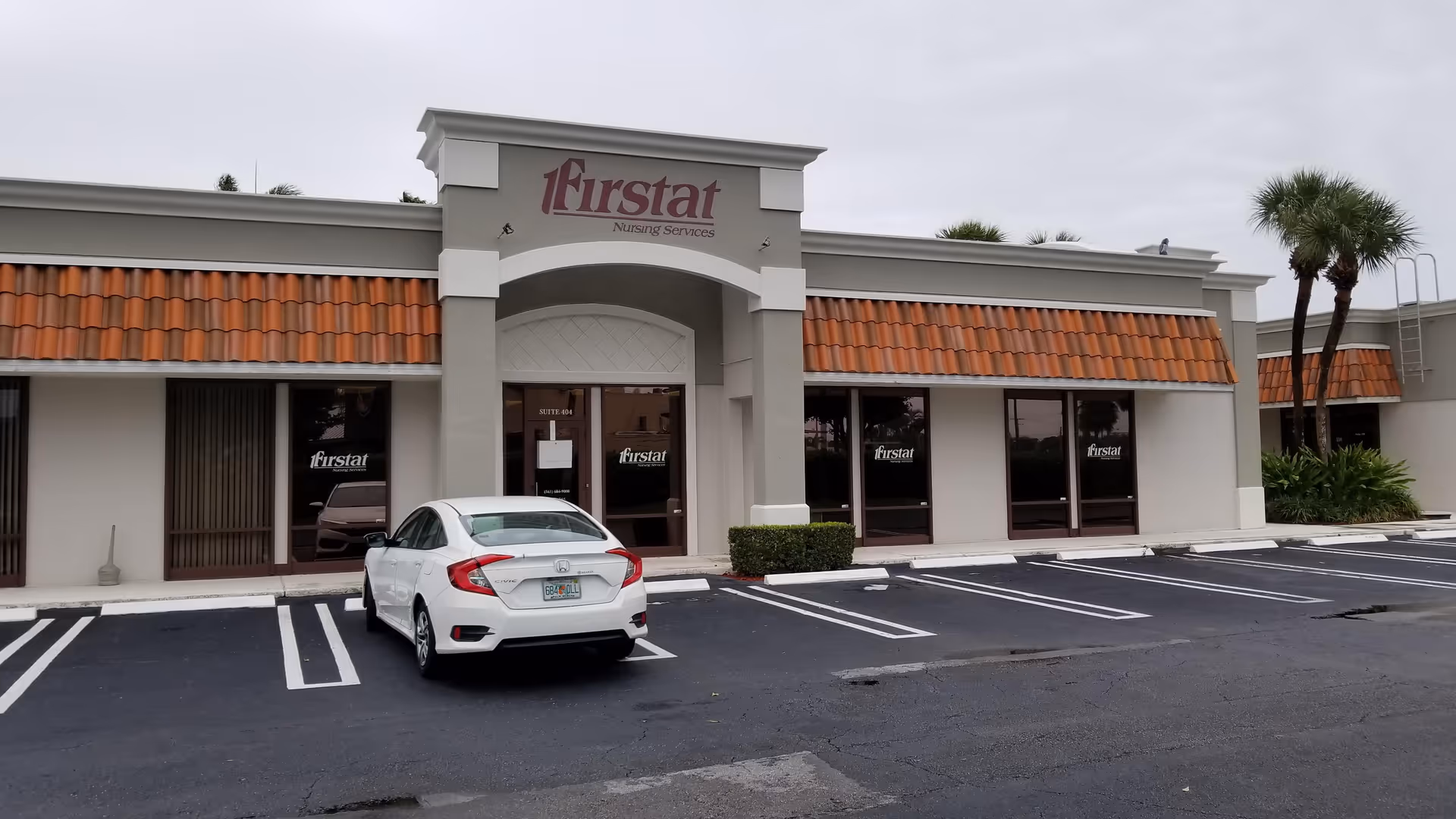 Exterior view of a Firstat Nursing Services building with a parked white car in front.