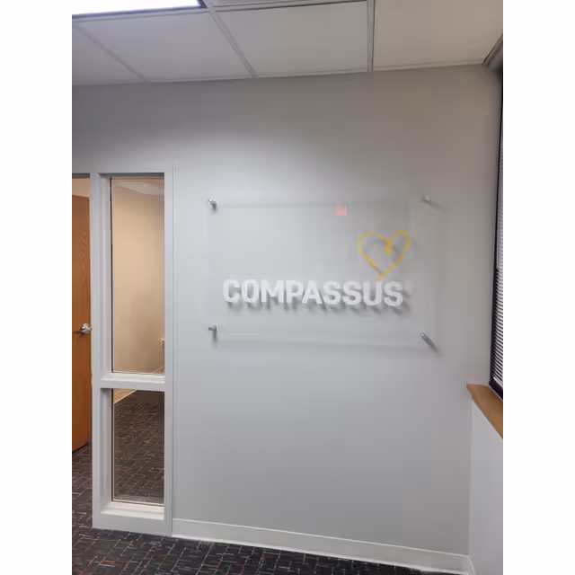 Interior wall with a Compassus sign and heart logo beside a doorway.