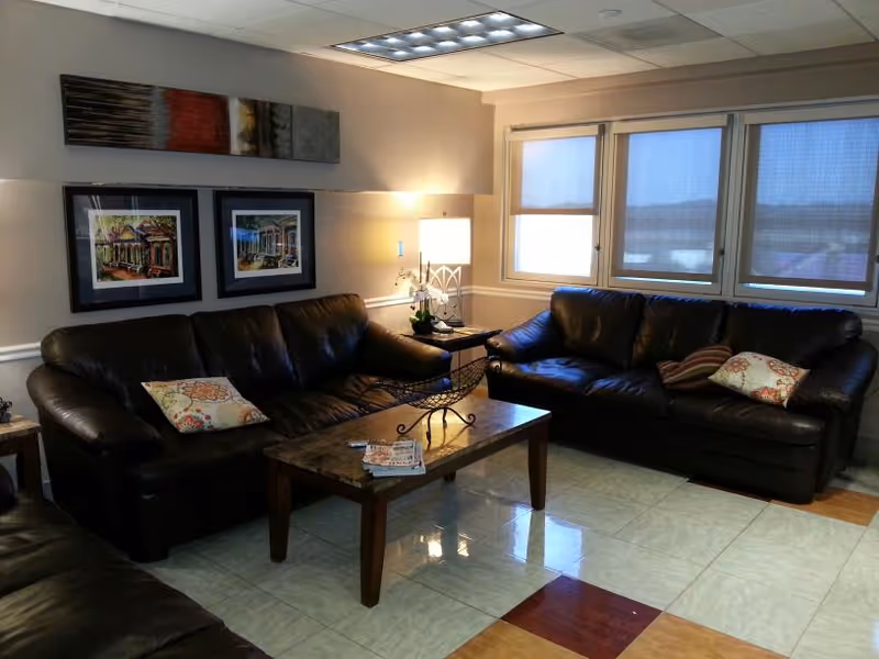 Cozy living room with leather sofas, a coffee table, lamp, and framed artwork.